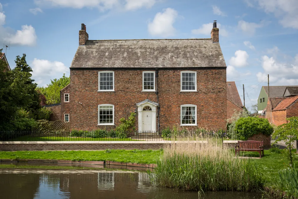 Prospect House, a red-brick Georgian farmhouse, seen across the village duck pond