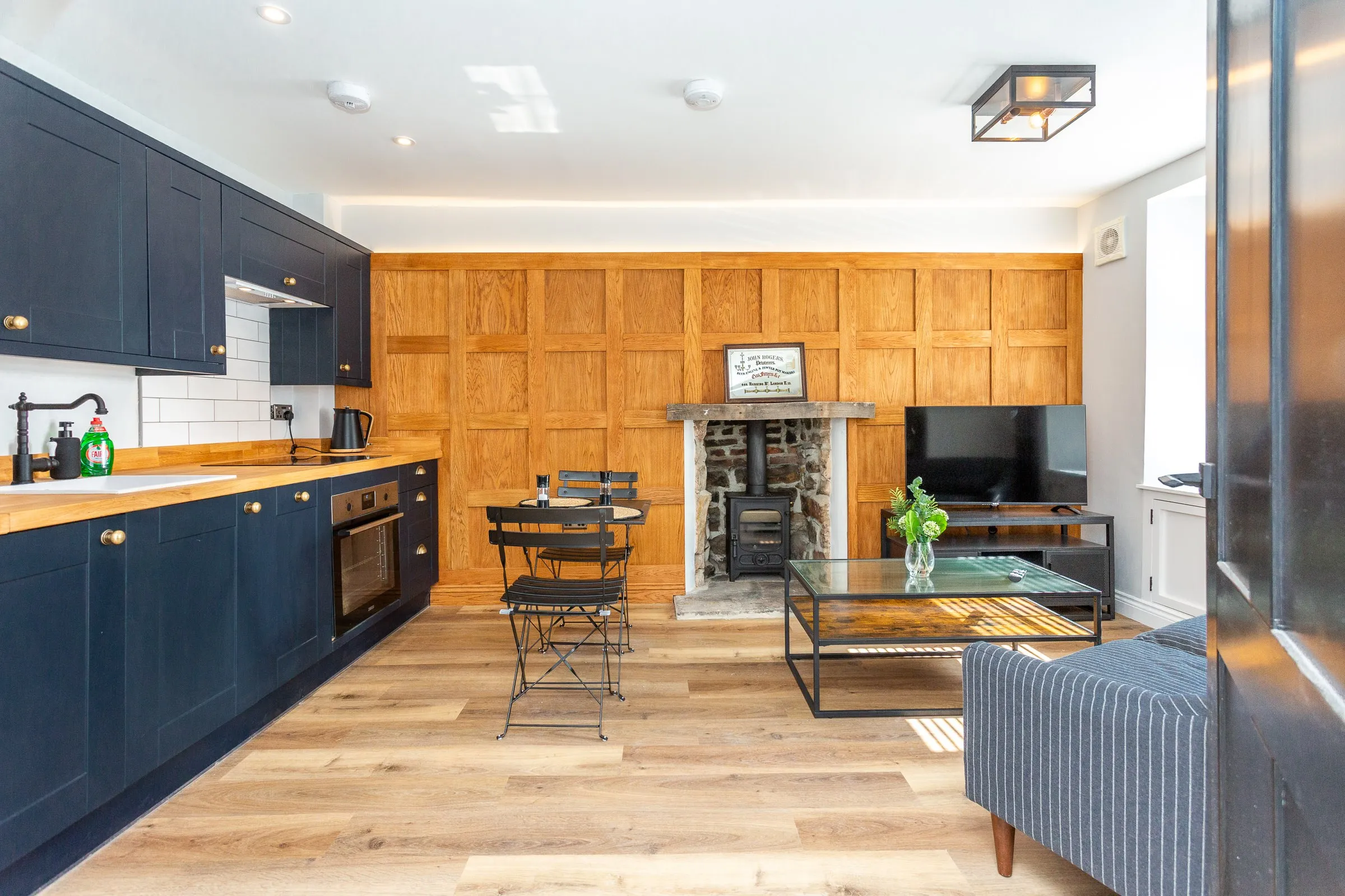 Open-plan kitchen and sitting room with oak panelling and a wood burner