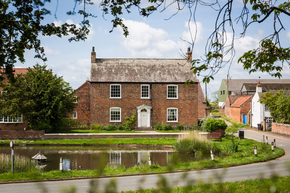 Prospect House framed by trees on the Askham Richard village green