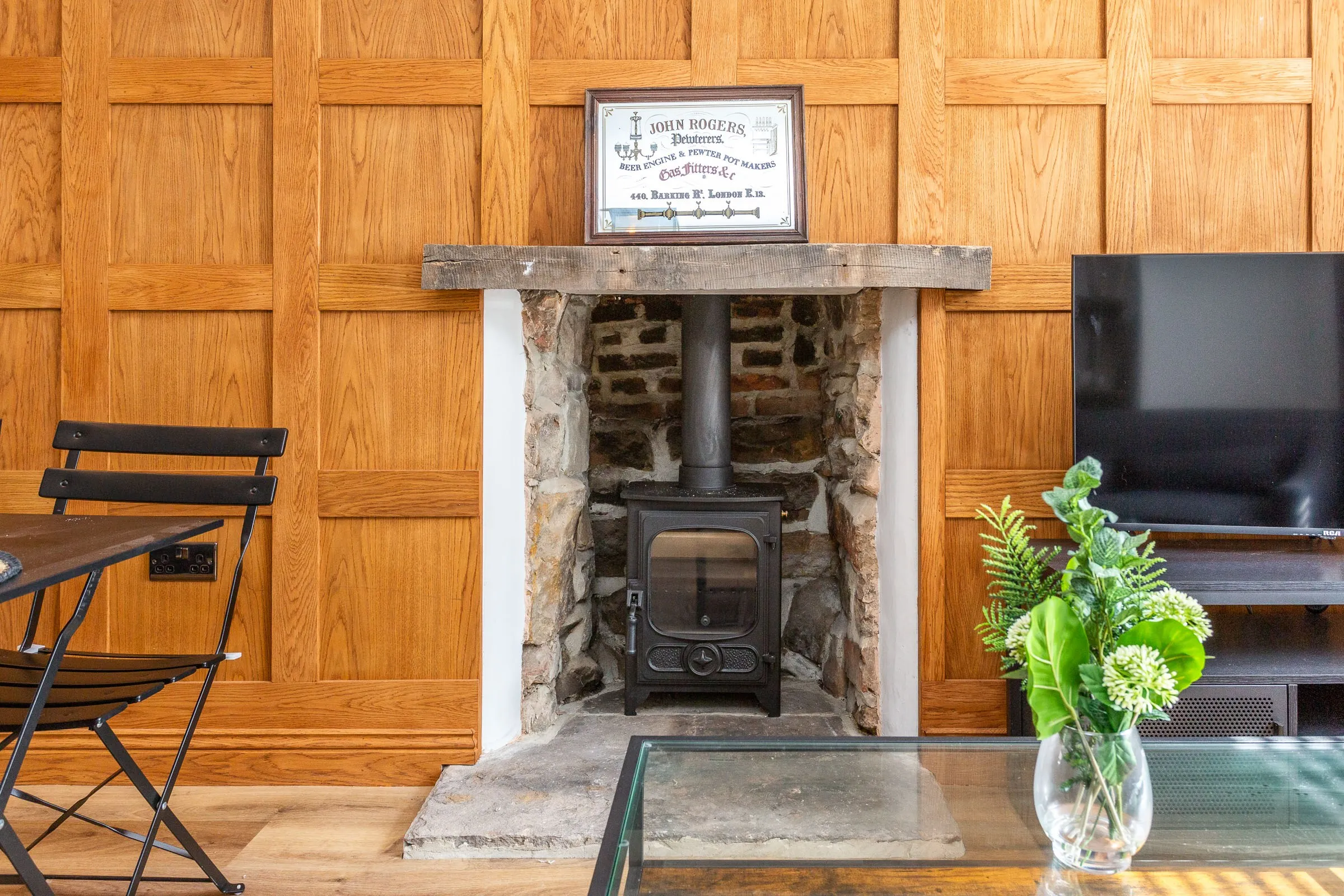 Wood burner in the original stone fireplace beneath an old timber mantel