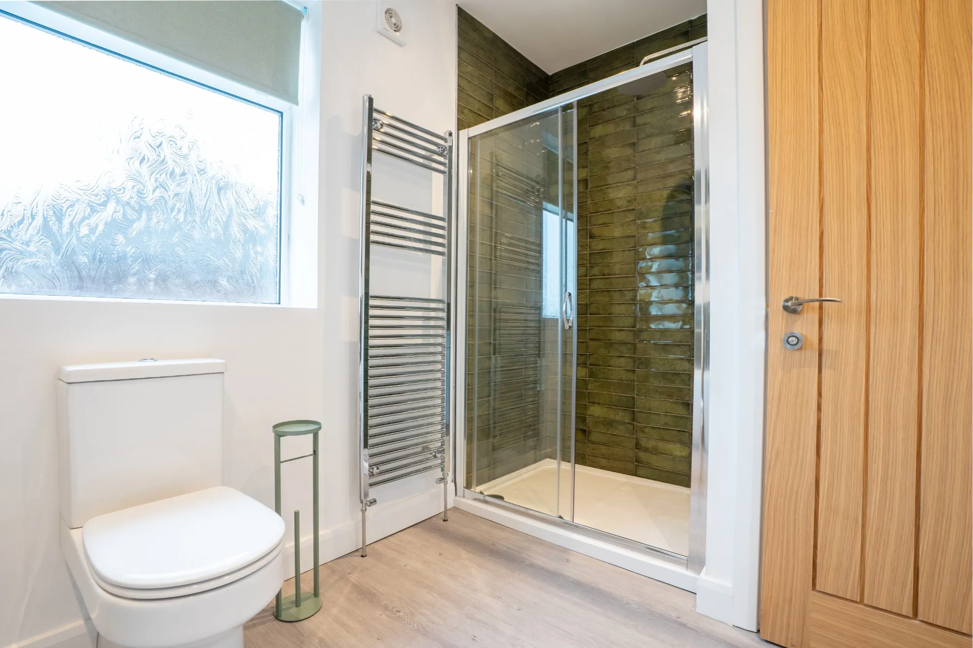 Shower room with a walk-in shower in green glazed tiles and a chrome towel radiator