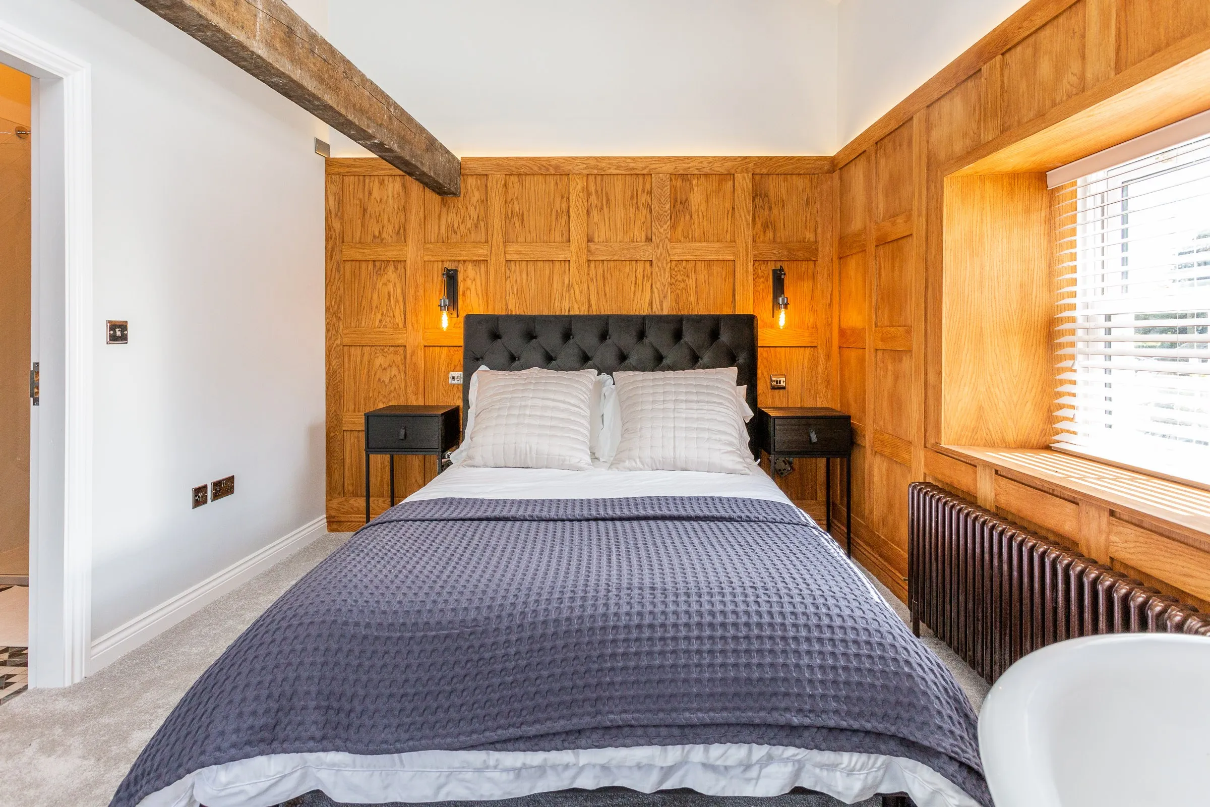 King-size bed with a buttoned headboard against oak panelling