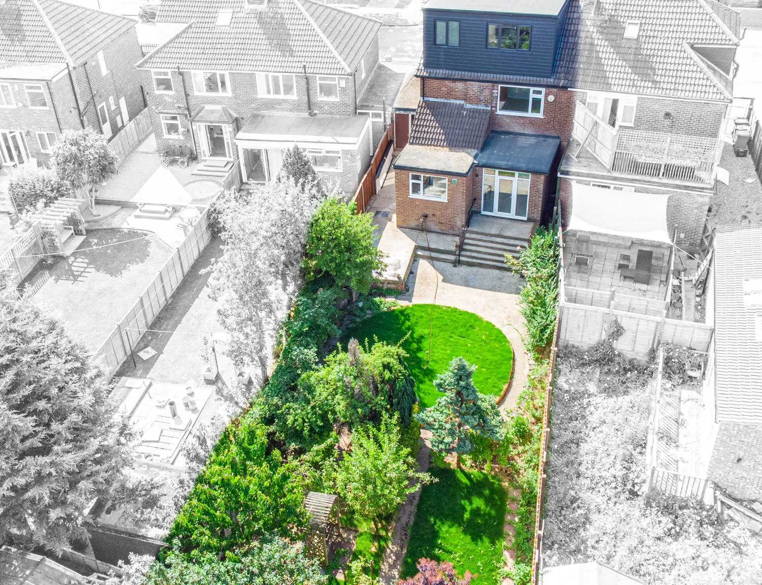 Looking down on the house and its long private garden, with a patio, steps, two lawns and an arbour at the far end