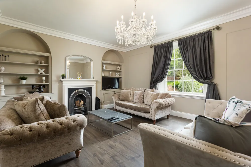 Sitting room with chandelier, velvet sofas and cast-iron fireplace
