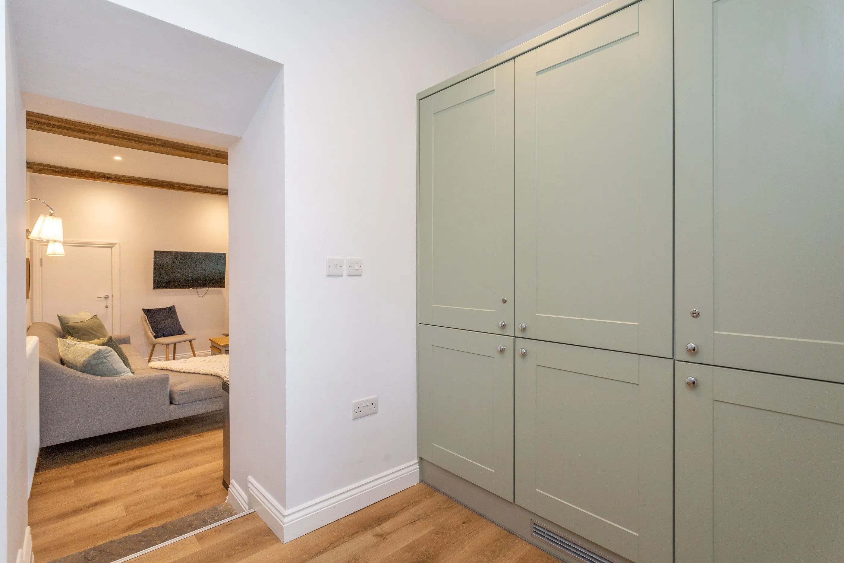 Utility room with sage cabinets and steps up to the sitting room
