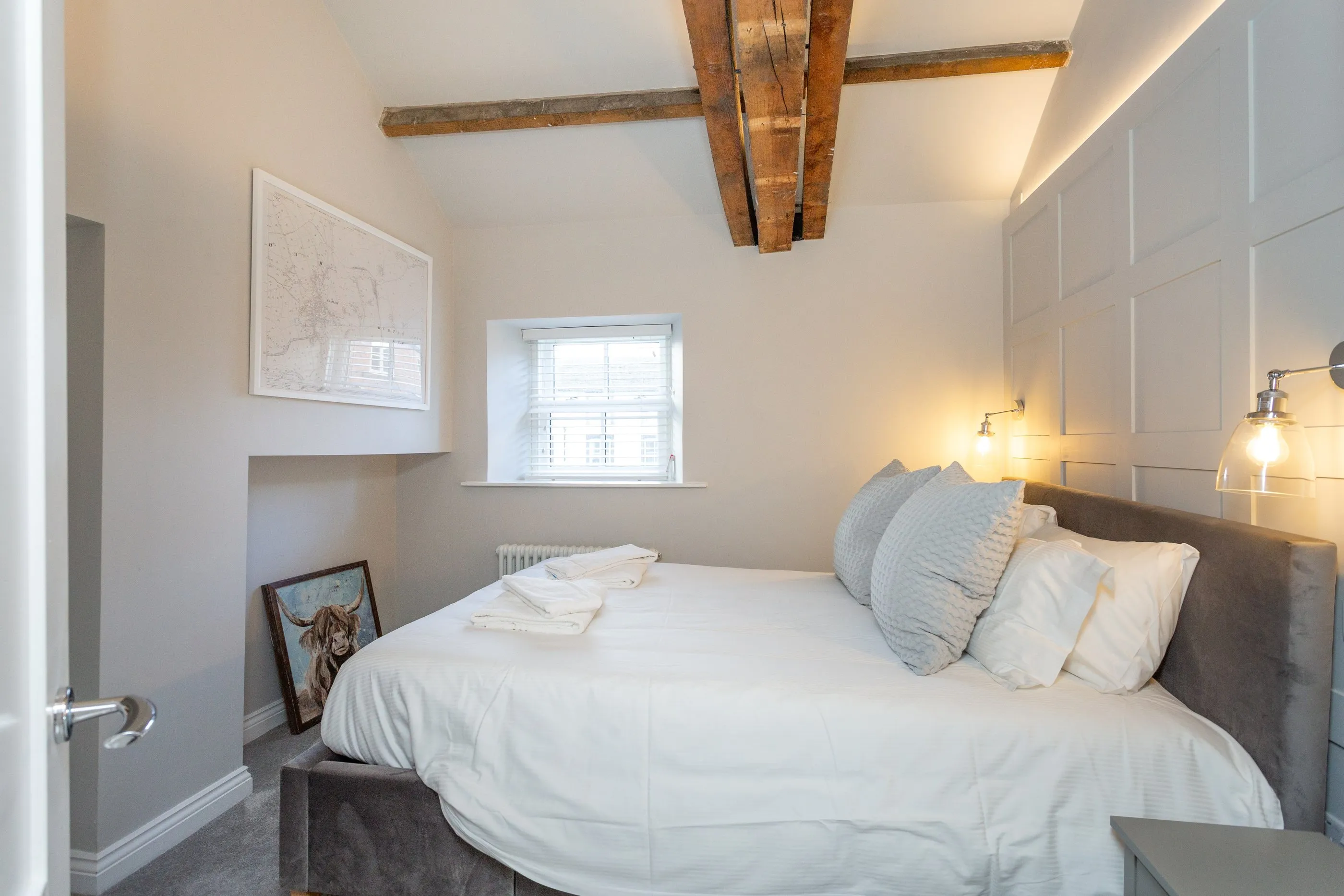 Vaulted bedroom with old beams, a historic map of Masham and soft lighting