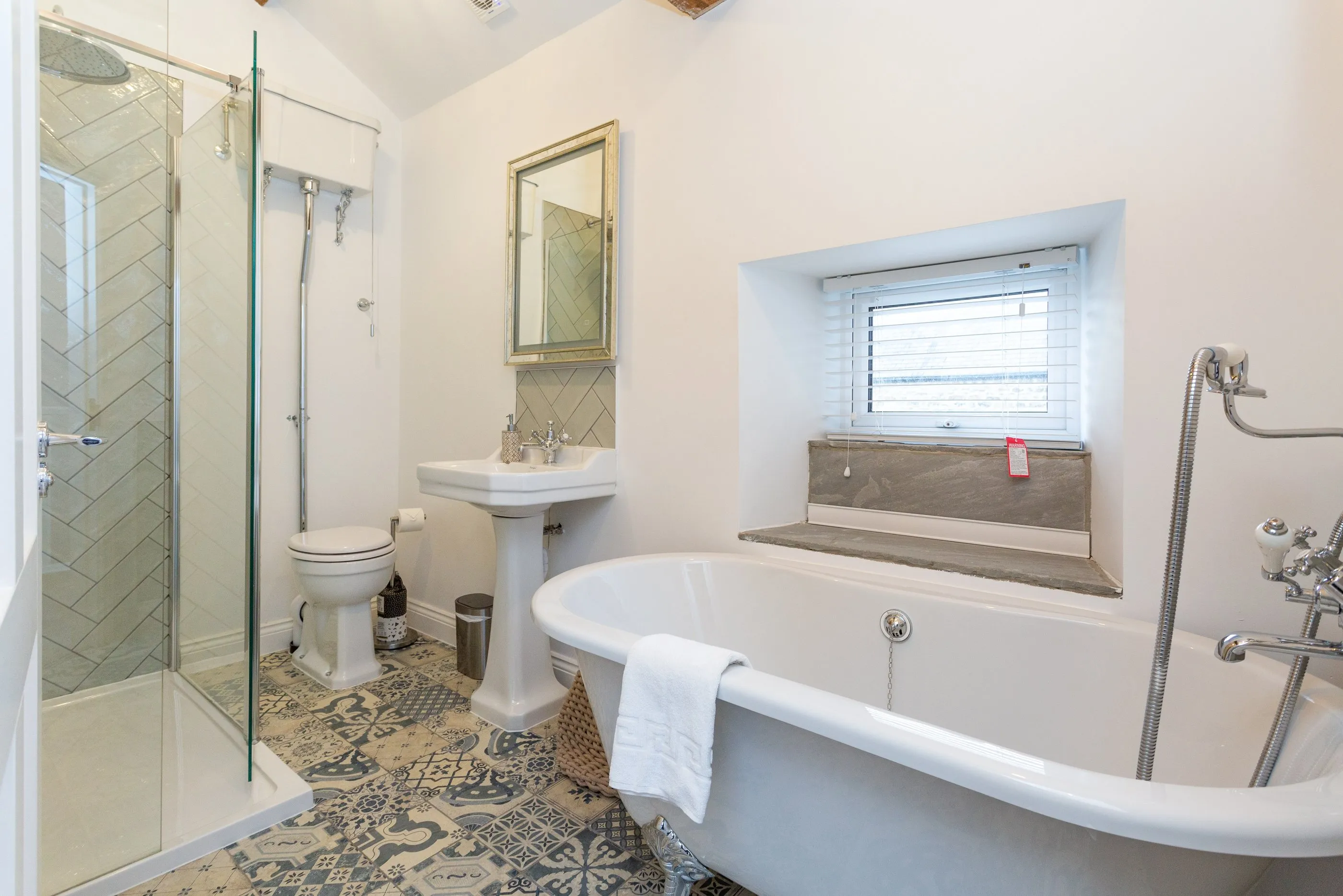 Bathroom with roll-top bath, walk-in rainfall shower and patterned floor tiles