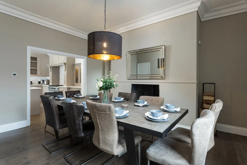 Dining room set for a group meal, opening to the kitchen