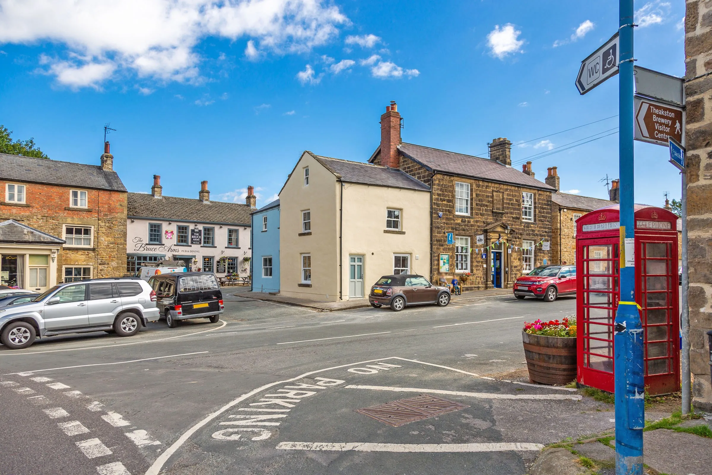 The cream-rendered cottage beside the Bruce Arms, with the red telephone boxes on the corner