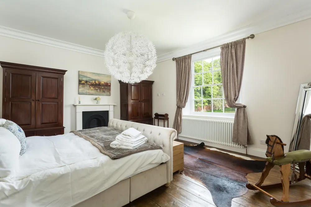 Bedroom with tall sash window, wardrobes and period fireplace