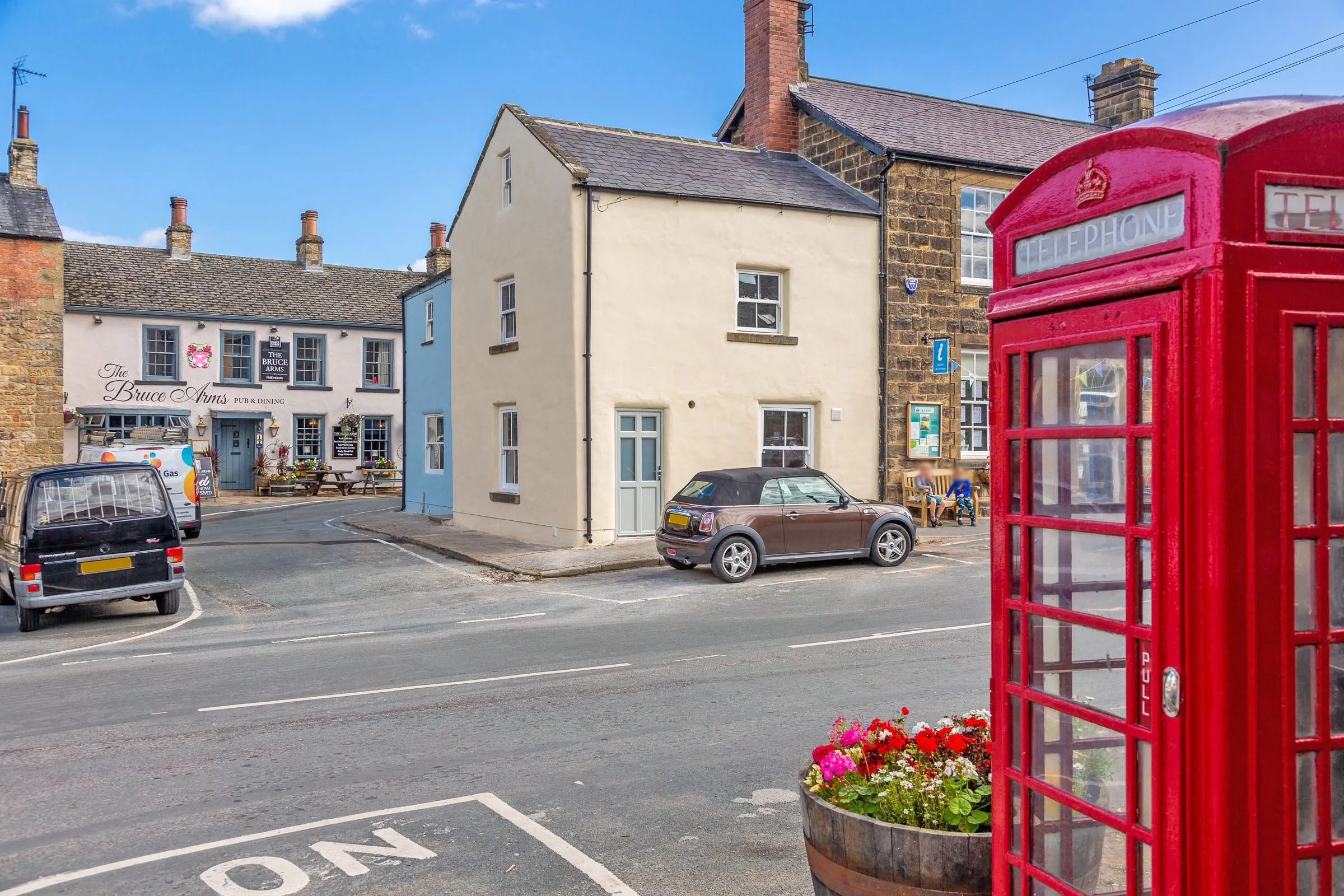 The cottage from across the road, framed by Masham's red telephone box