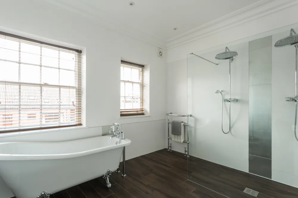 Bathroom with roll-top bath and twin walk-in showers
